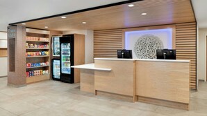 A modern reception desk with a Lenovo logo, a beverage refrigerator, and shelves stocked with snacks.