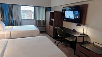 Habitación de hotel con dos camas, un escritorio, una silla, un televisor y un armario.