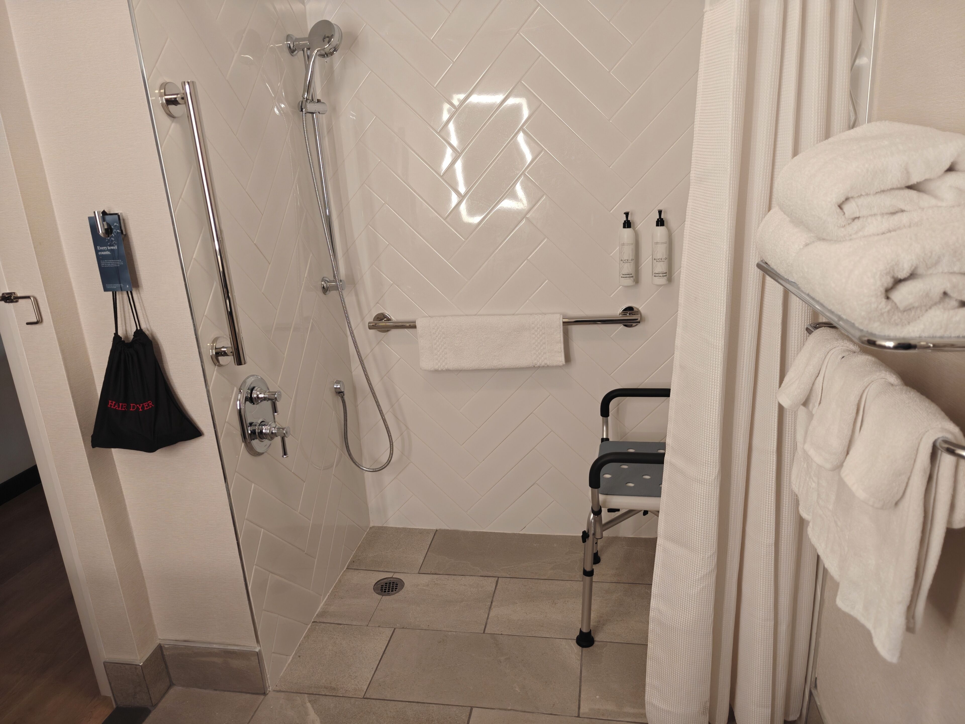 A modern bathroom with a shower, a towel rack, and a grab bar.