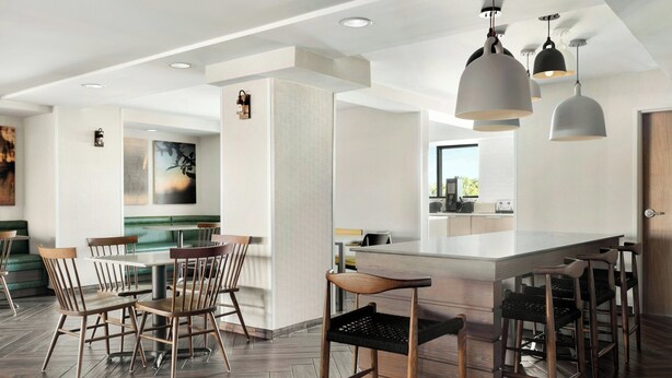 A modern kitchen with a central island, bar stools, and pendant lighting.