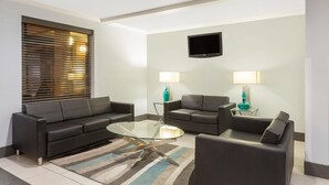 Een moderne woonkamer met een glazen salontafel, twee banken, een flatscreen-televisie en twee lampen op bijzettafels.