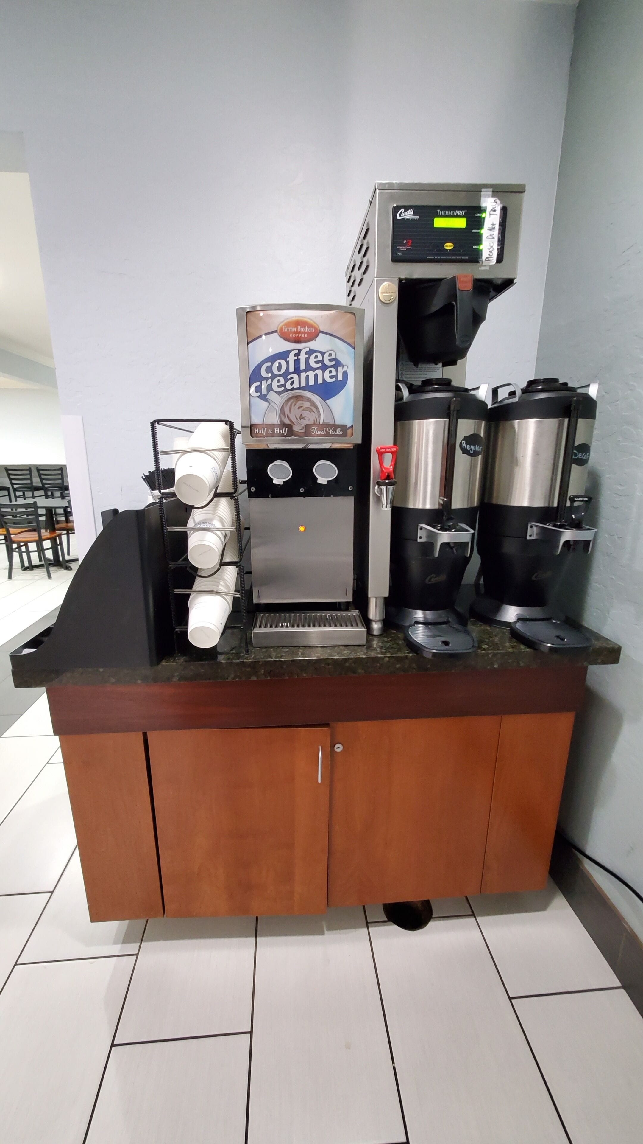 A coffee station with a coffee creamer dispenser, a coffee machine, and a milk frother.