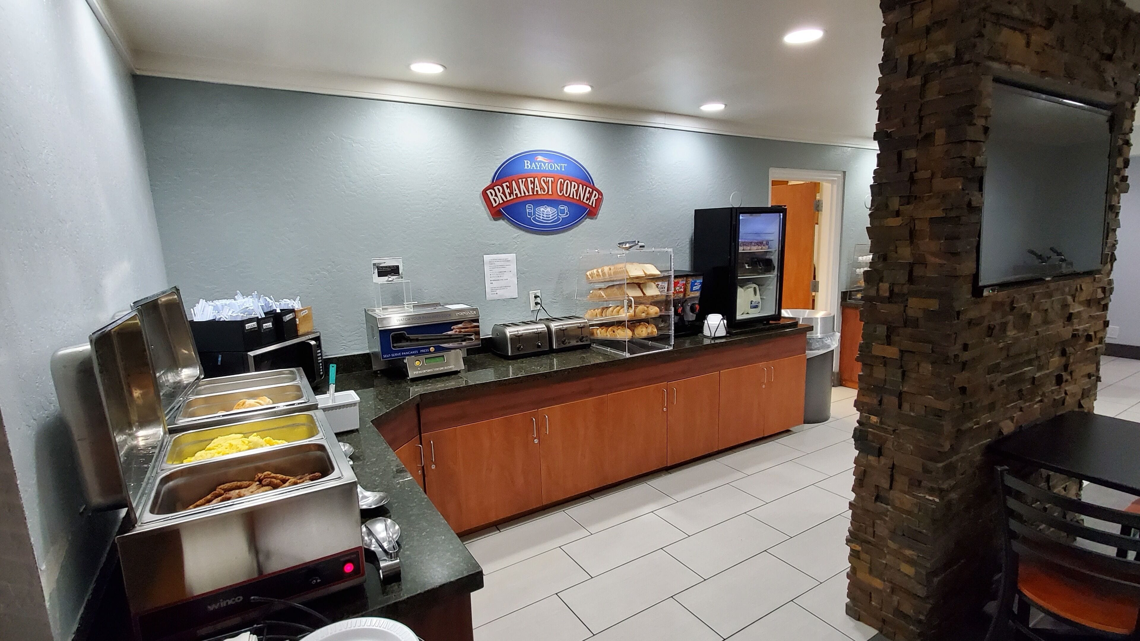 Un banco della colazione con servizio self-service, insegna Baymont e una parete in pietra.