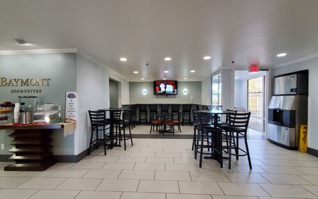 A hotel lobby with a reception desk, seating area, and a TV screen.