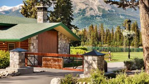 A lodge with a stone facade, wooden exterior, and a sign reading "The Estate Cabins at Fairmont Jasper Park Lodge." - Fairmont Jasper Park Lodge (Jasper)