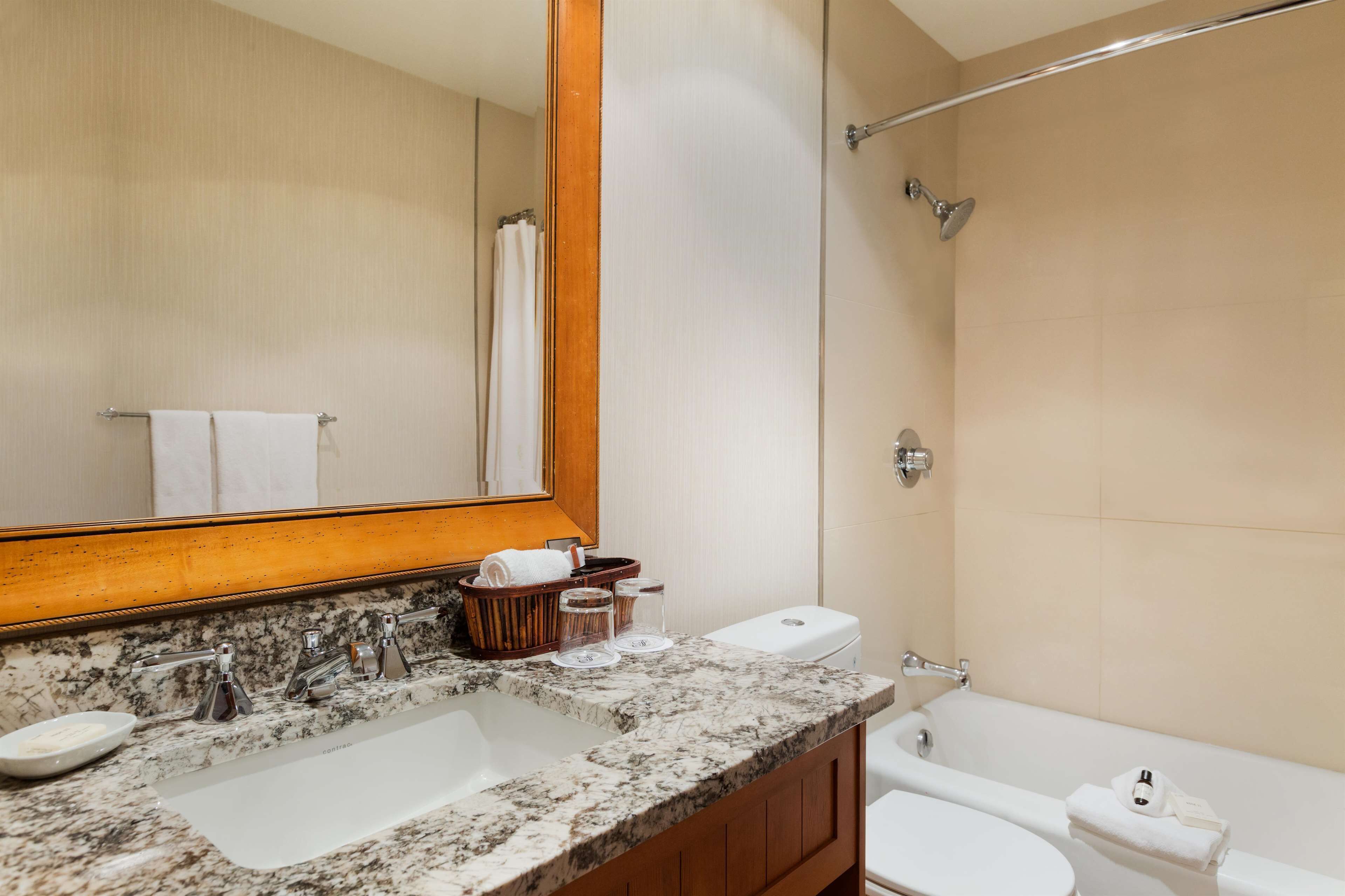 A bathroom with a marble sink, a toilet, a bathtub, and a shower.