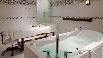 Relax in a spacious bathroom with a bathtub, a chair, and a table with a decorative centerpiece.