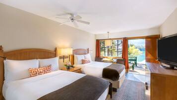 A hotel room with two beds, a ceiling fan, a TV, and a view of the outdoors.