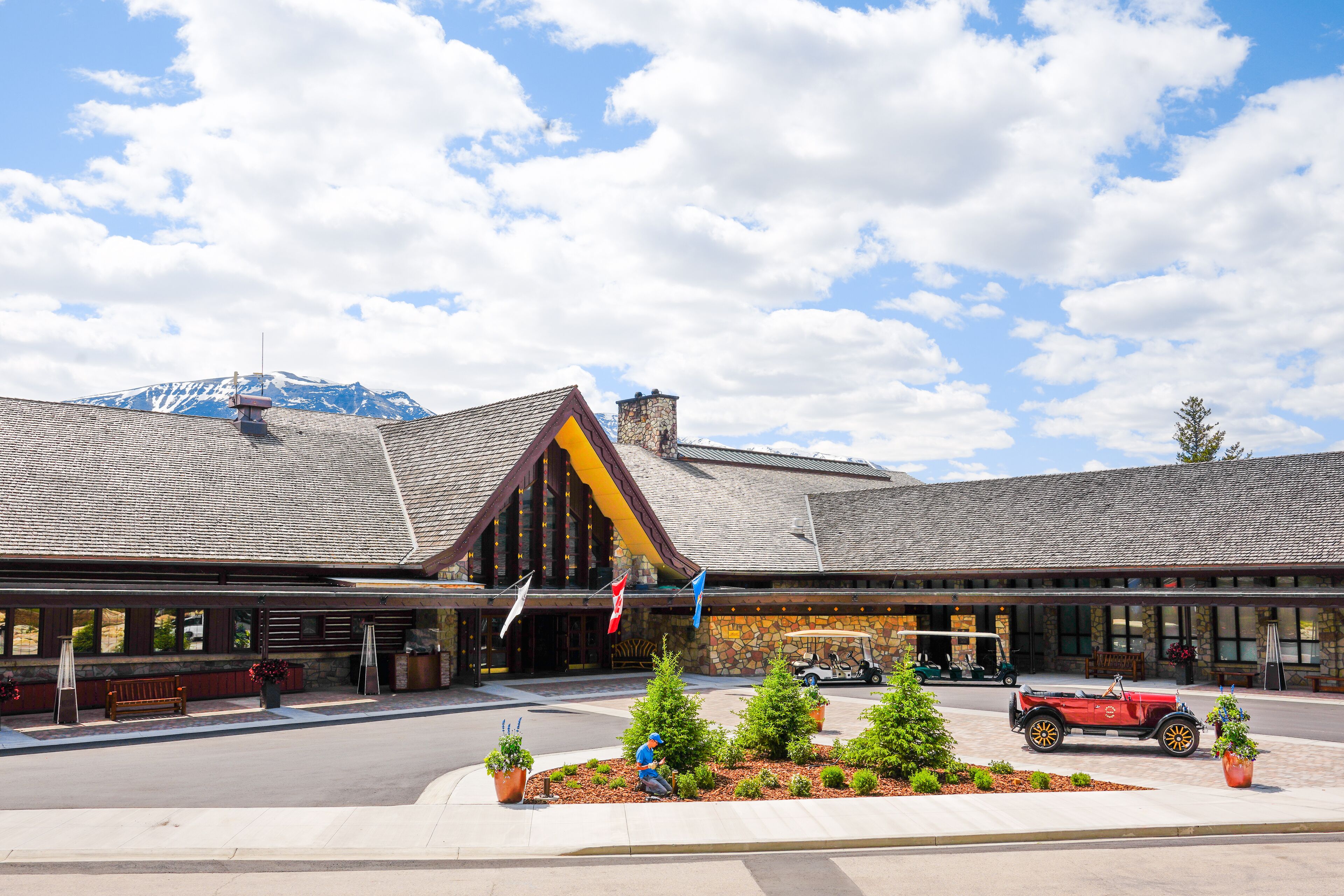 A lodge with a stone facade, a prominent triangular roof, and a mountain in the background.