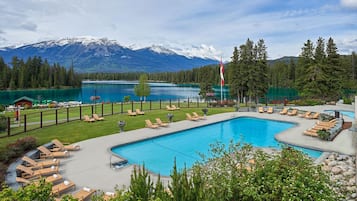 Una piscina al aire libre, sombrillas, sillones reclinables de piscina