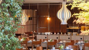 A restaurant with wooden panel walls, hanging pendant lights, and tables set with white plates and cups. - Les Jardins d'Eiffel (Paris)