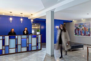 A reception area with a blue wall, a reception desk, and a potted plant.