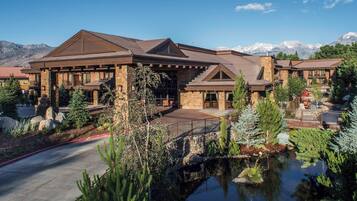 A large, multi-story lodge with a stone facade, multiple balconies, and a view of snow-capped mountains.