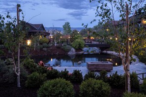 A serene outdoor setting with a pond, seating areas, and a bridge. - Wayfinder Bishop (Bishop)