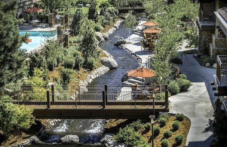 A river running through a landscaped area with a bridge, a pool, and outdoor seating areas.