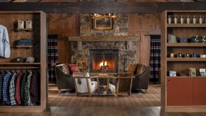 Un salón amplio con chimenea de piedra, vigas de madera y techo alto.