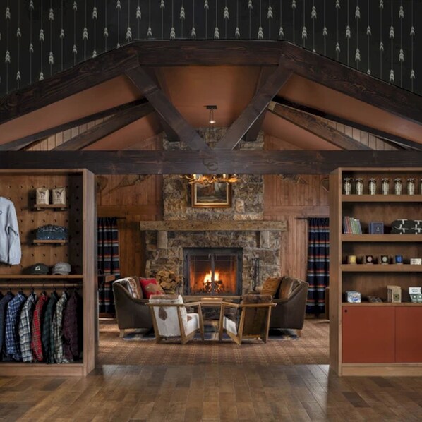 A spacious living room with a stone fireplace, wooden beams, and a high ceiling. - Wayfinder Bishop (Bishop)