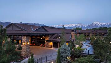 A lodge with a stone facade, a covered entrance, and a view of snow-capped mountains.