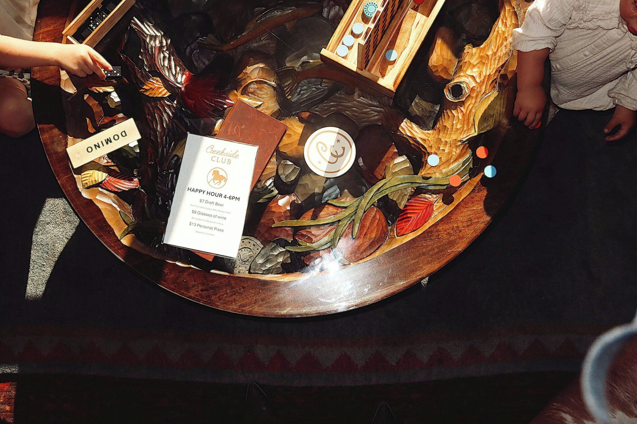 A wooden table with a menu and a sign for Creekside Club.