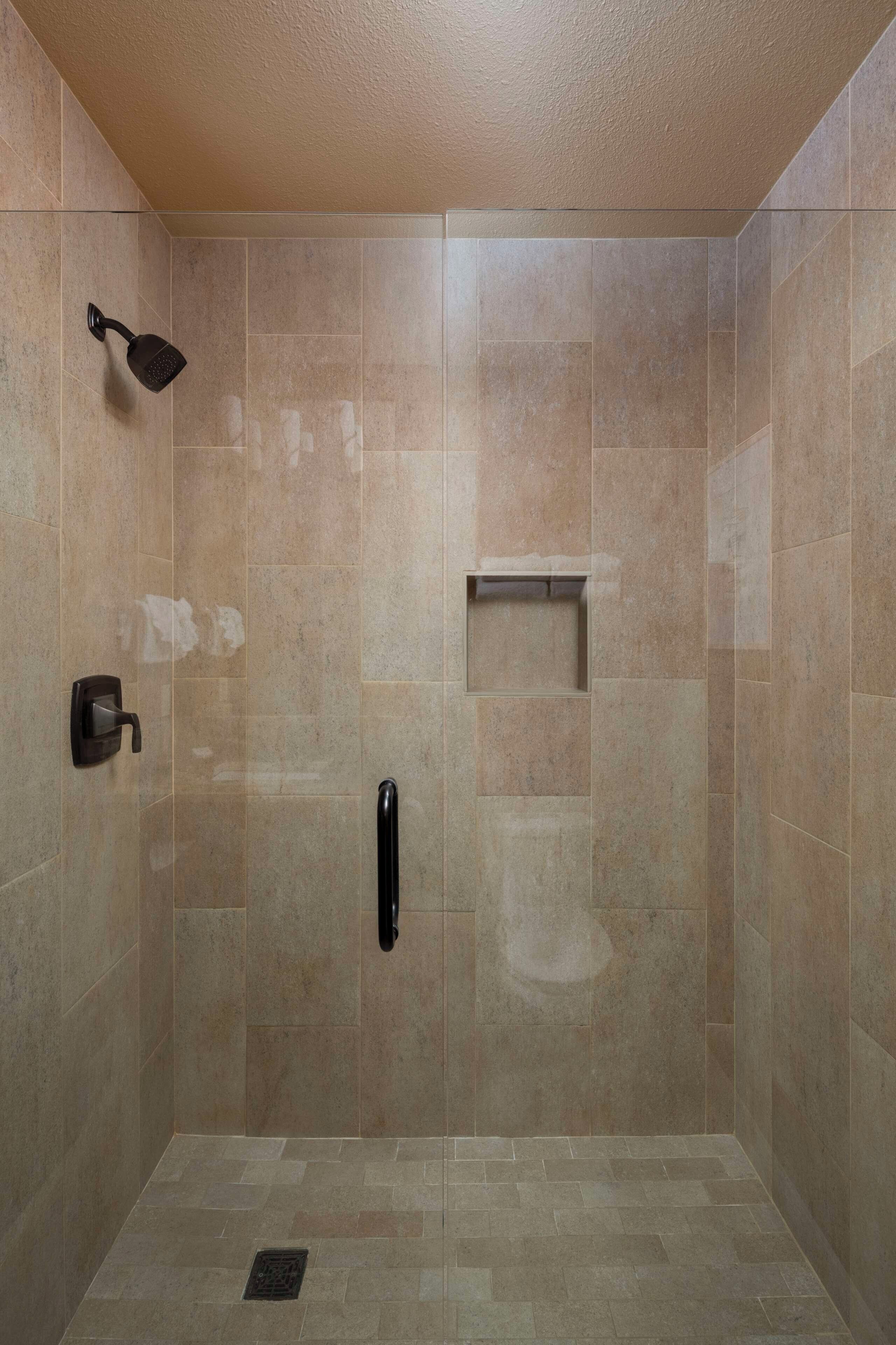Zona de ducha con ducha de mano, toallero y secador de manos.