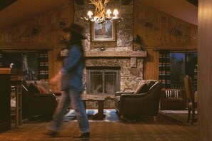 A spacious room with a stone fireplace, leather armchairs, and a chandelier. - Wayfinder Bishop (Bishop)