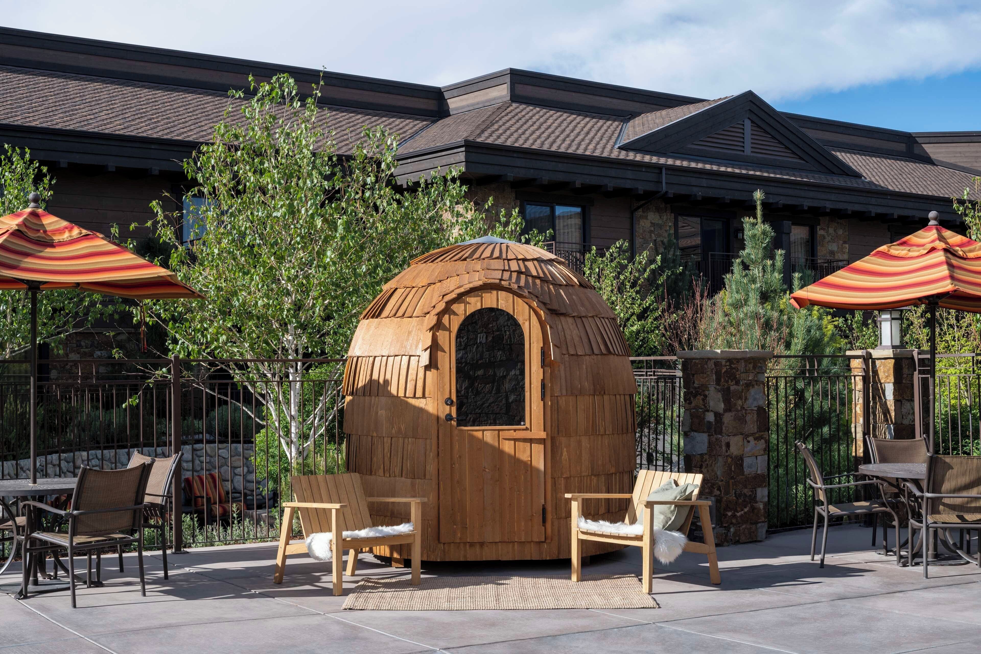 Un espace extérieur aménagé avec une structure en bois, des chaises et des parasols.