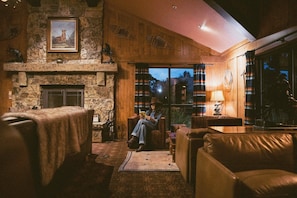 A cozy interior with a stone fireplace, leather furniture, and a large window. - Wayfinder Bishop (Bishop)