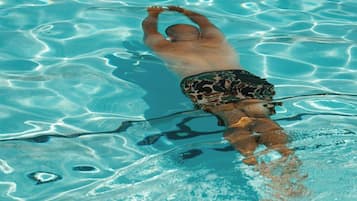 A person swimming in a clear blue pool.