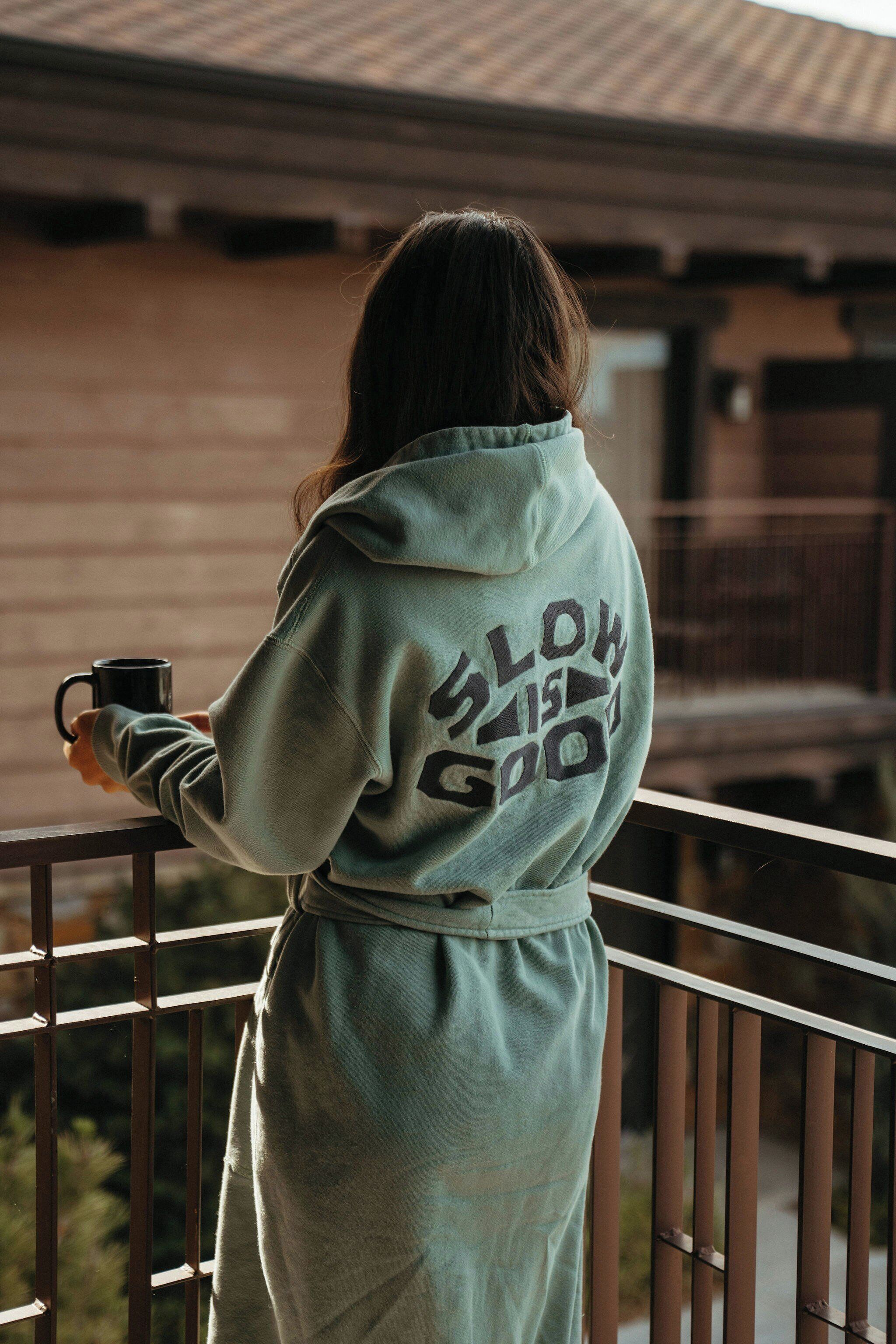 A person standing on a balcony wearing a hoodie with text on the back.