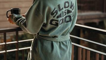 A person standing on a balcony wearing a hoodie with text on the back.