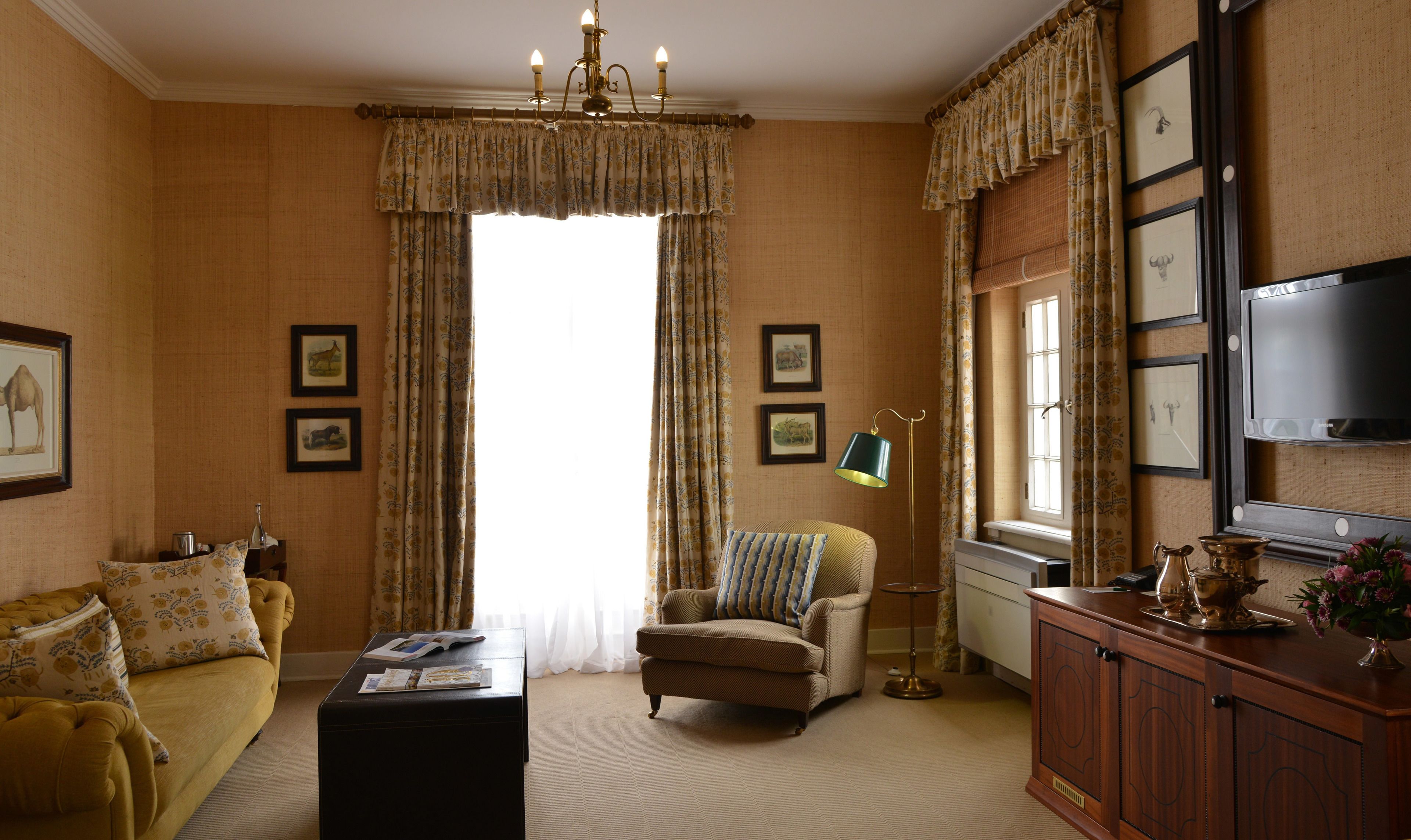 A living room with a sofa, armchair, coffee table, and a cabinet with decorative items.