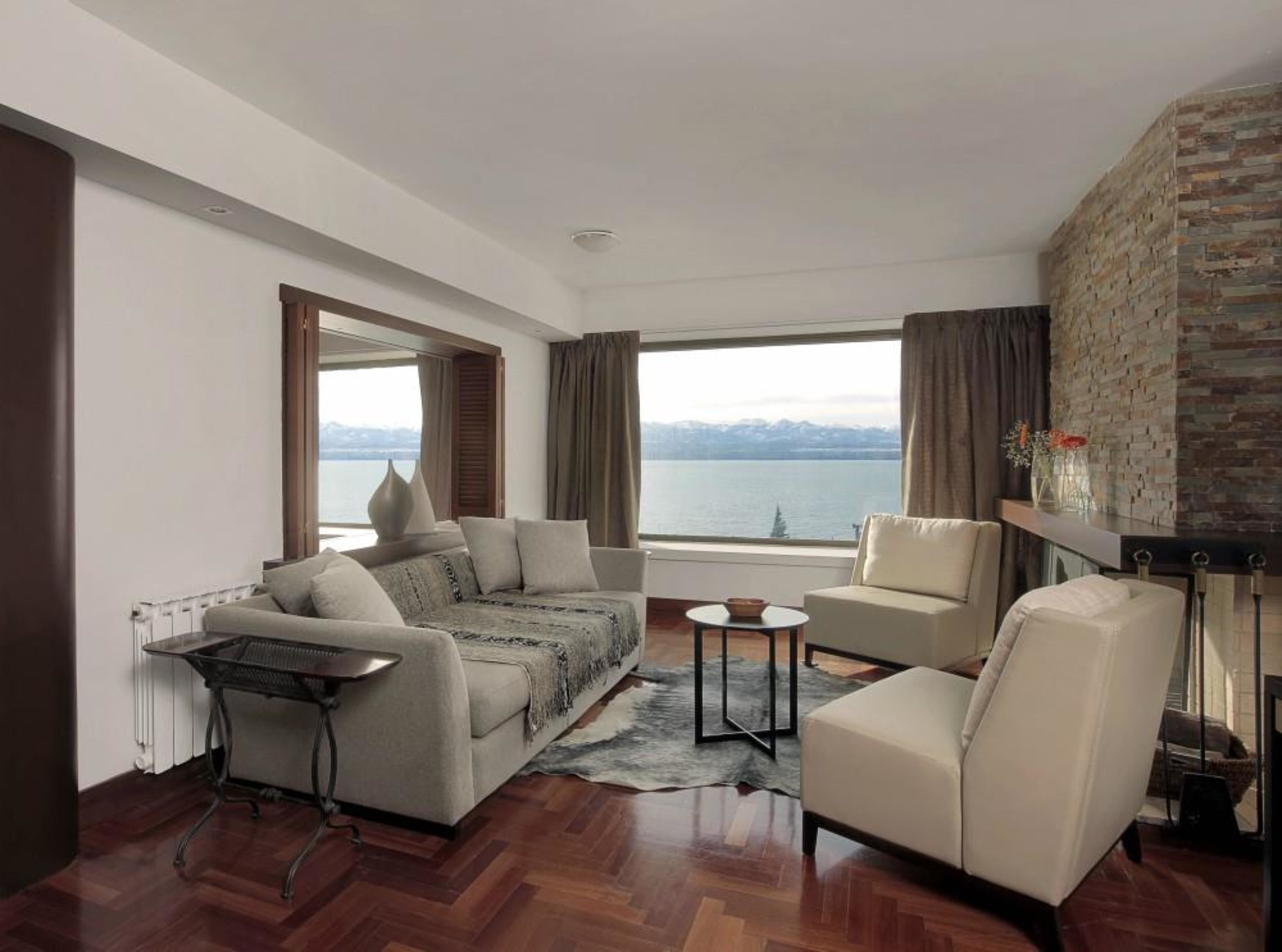 Una sala de estar moderna con un sofá, sillones, una mesa de centro y vista a un cuerpo de agua.