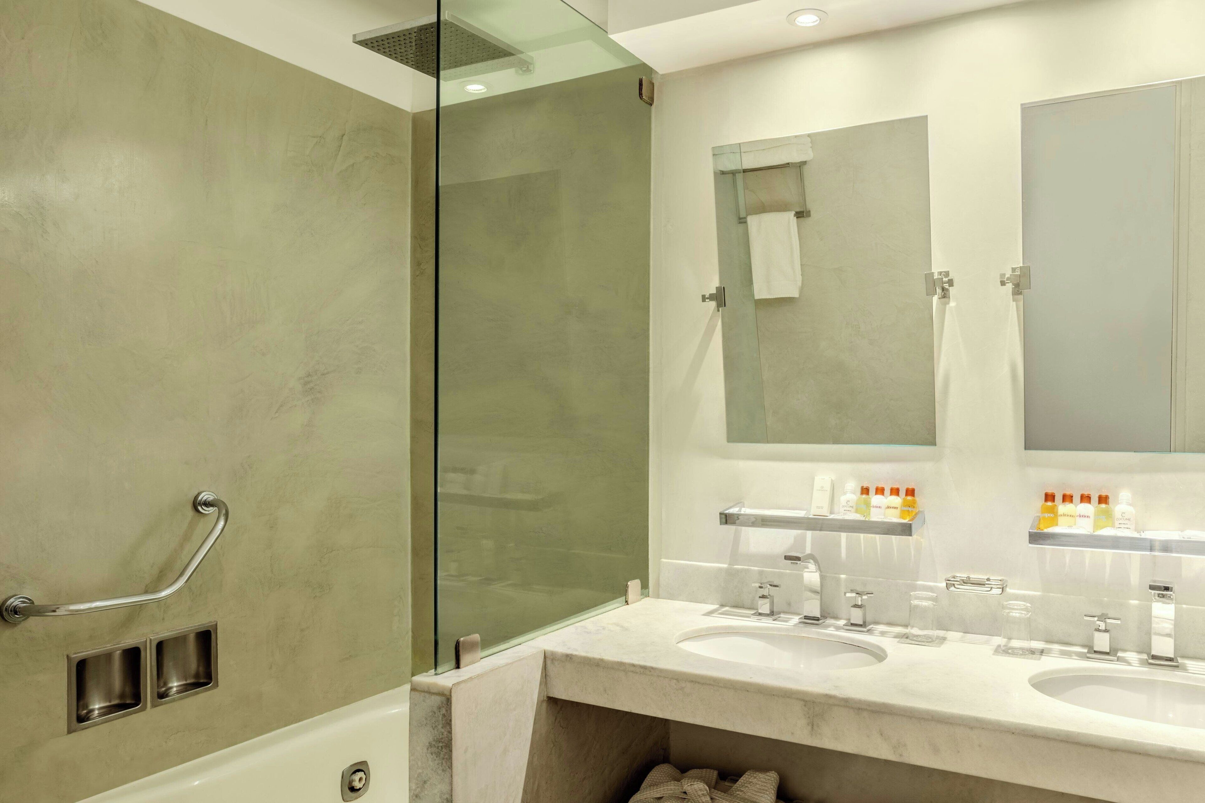 A modern bathroom with a glass shower enclosure, a vanity with two sinks, and a large mirror above the sinks.