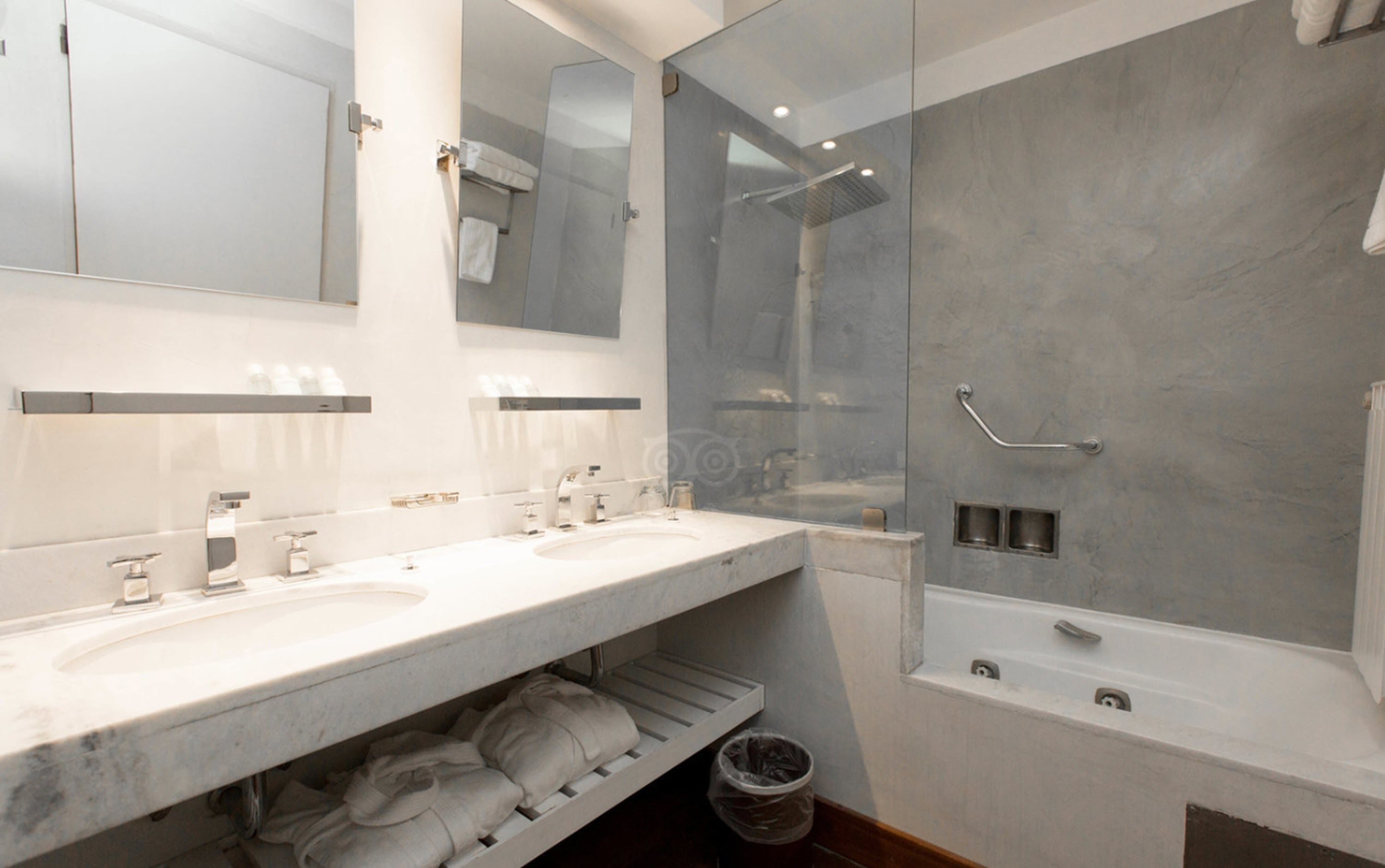 Un baño moderno con dos lavamanos, ducha con mampara de vidrio y bañera.
