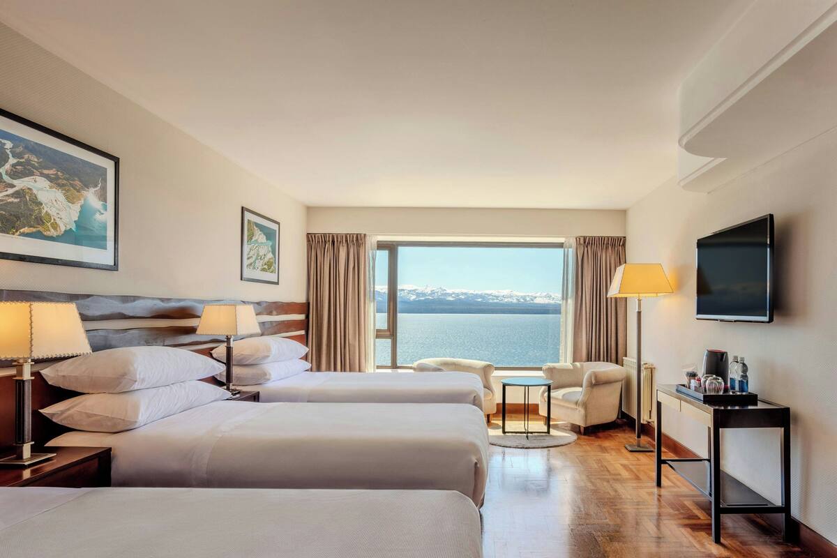 Une chambre d’hôtel avec deux lits, une télévision, un bureau et vue sur la mer.