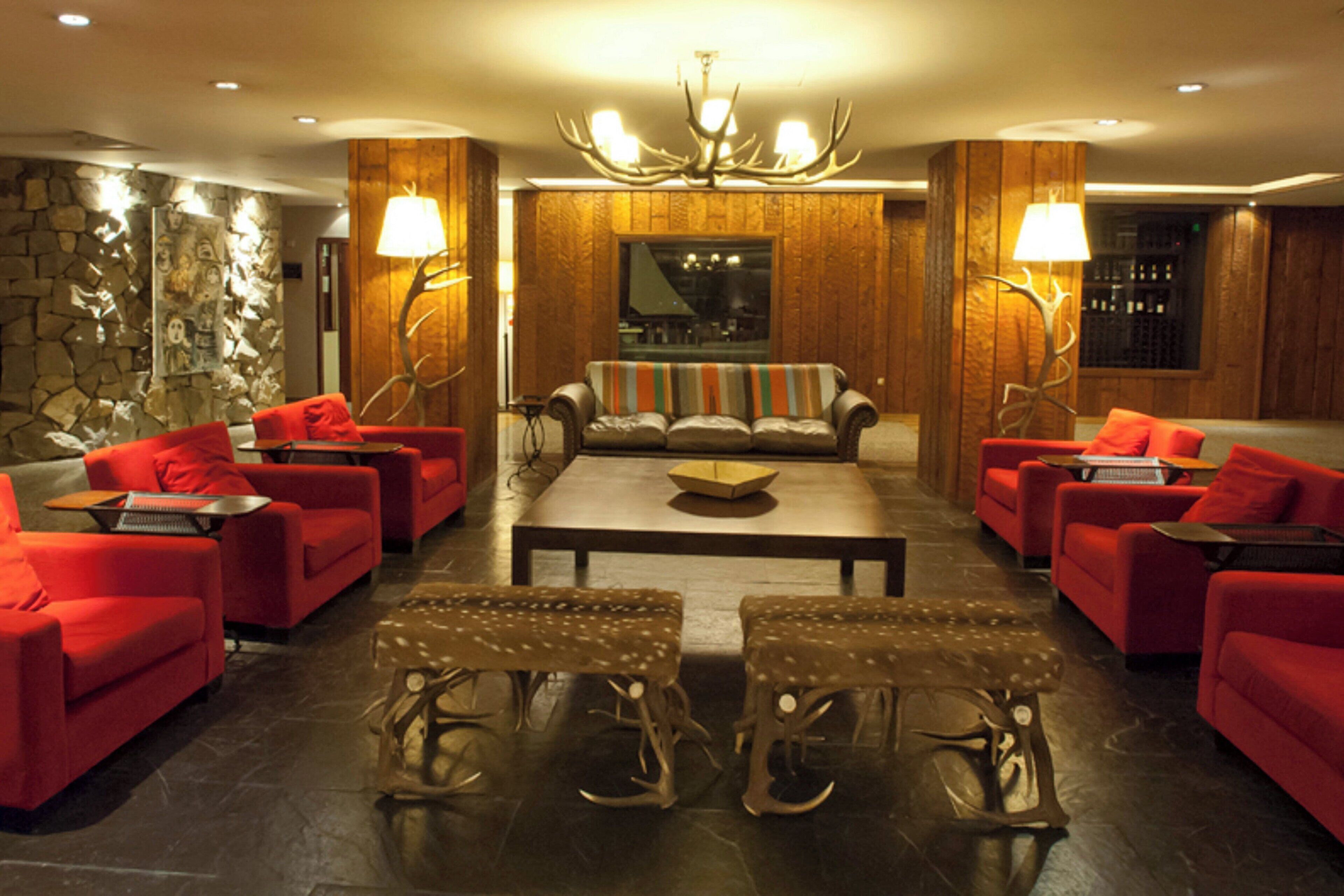 A lobby with red sofas, a central coffee table, and a chandelier.
