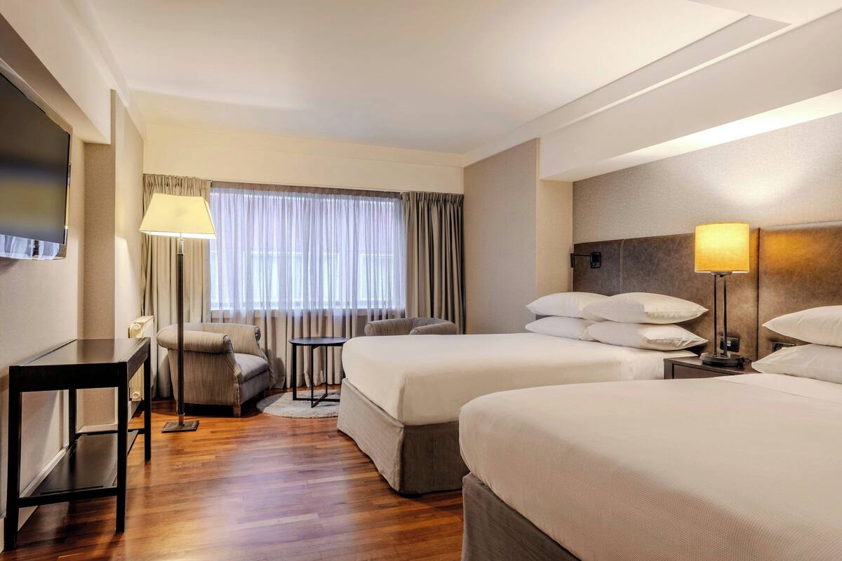 Une chambre d’hôtel avec deux lits, un canapé, une petite table et un téléviseur.
