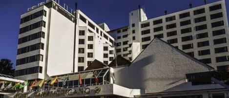 A hotel with multiple floors, a prominent entrance, and flags.