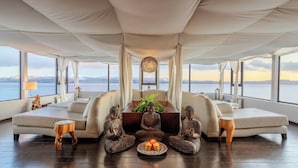 A spacious living area with a sofa, a wooden stool, and three Buddha statues.