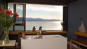 A room with a large window overlooking a body of water and mountains.