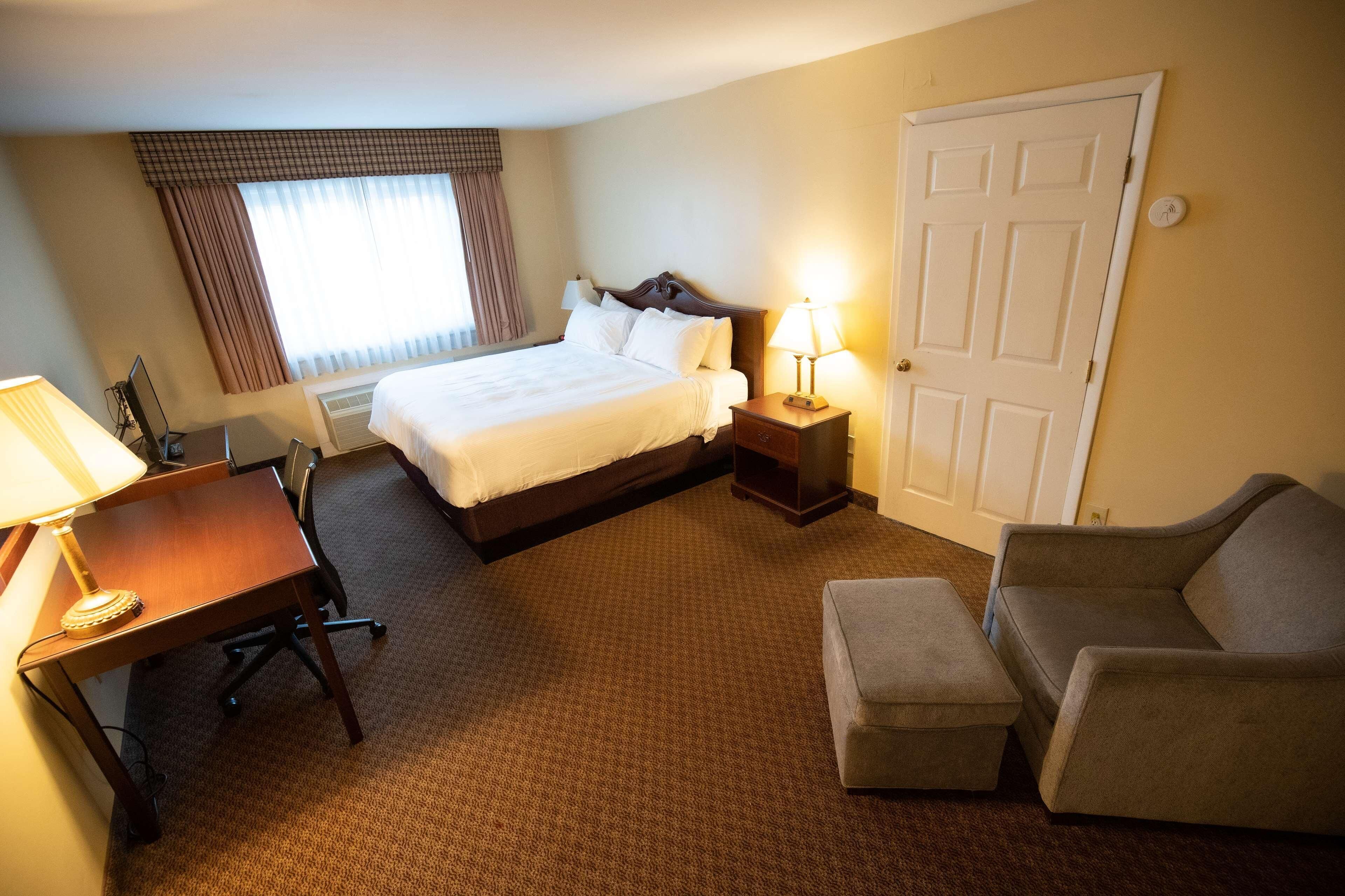 A hotel room with a bed, desk, chair, and a sofa.
