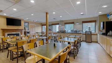Ein Restaurant mit mehreren Tischen und Stühlen, einer Theke mit Registrierkasse und einem an der Wand befestigten Fernseher.