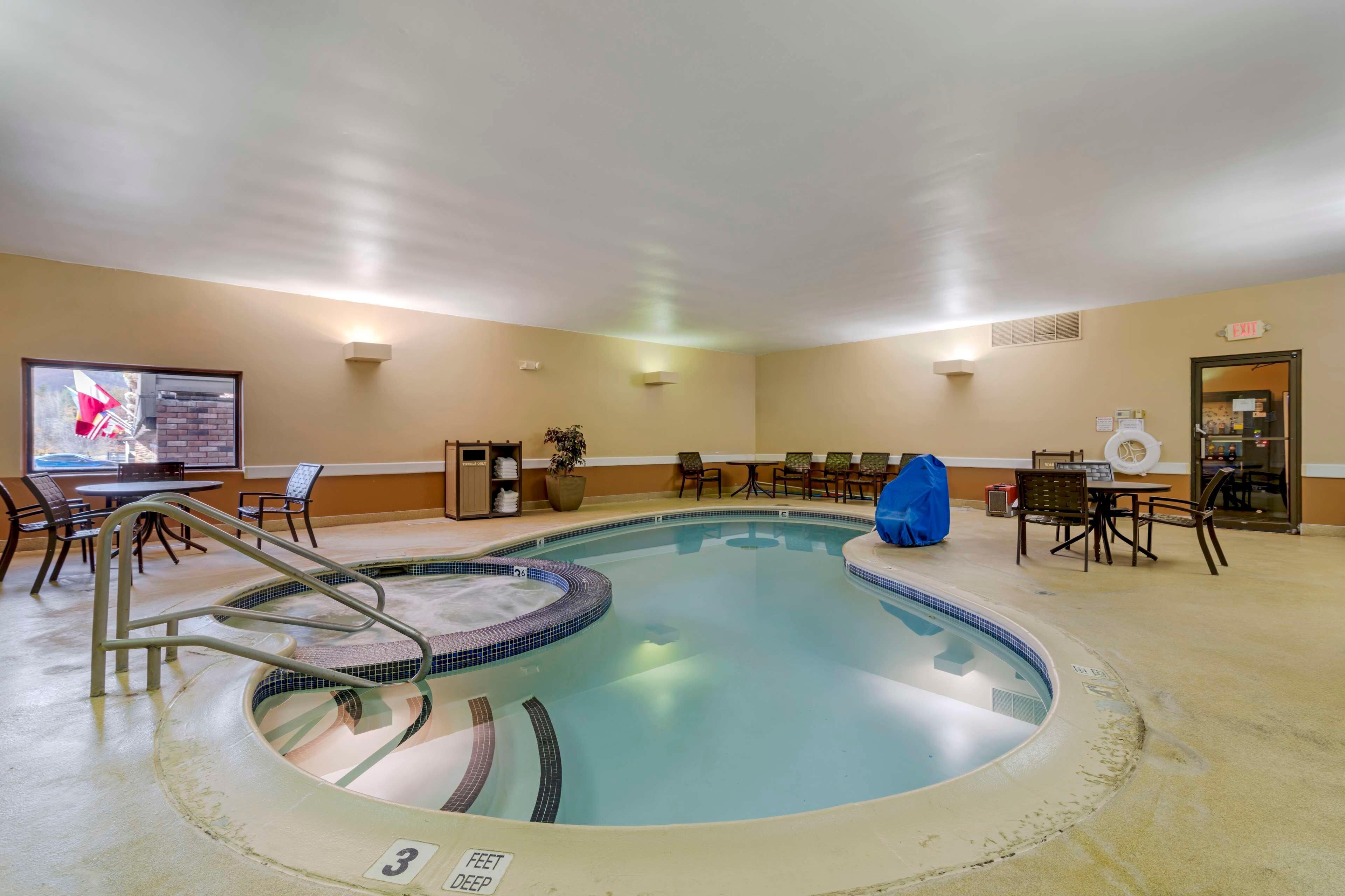 Zona de piscina de hotel con jacuzzi, sillas de descanso y mesa de billar.