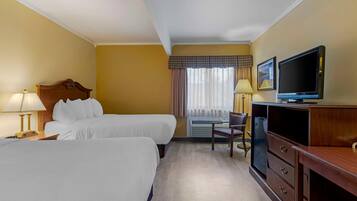 A hotel room with two beds, a television, a desk, and a chair.
