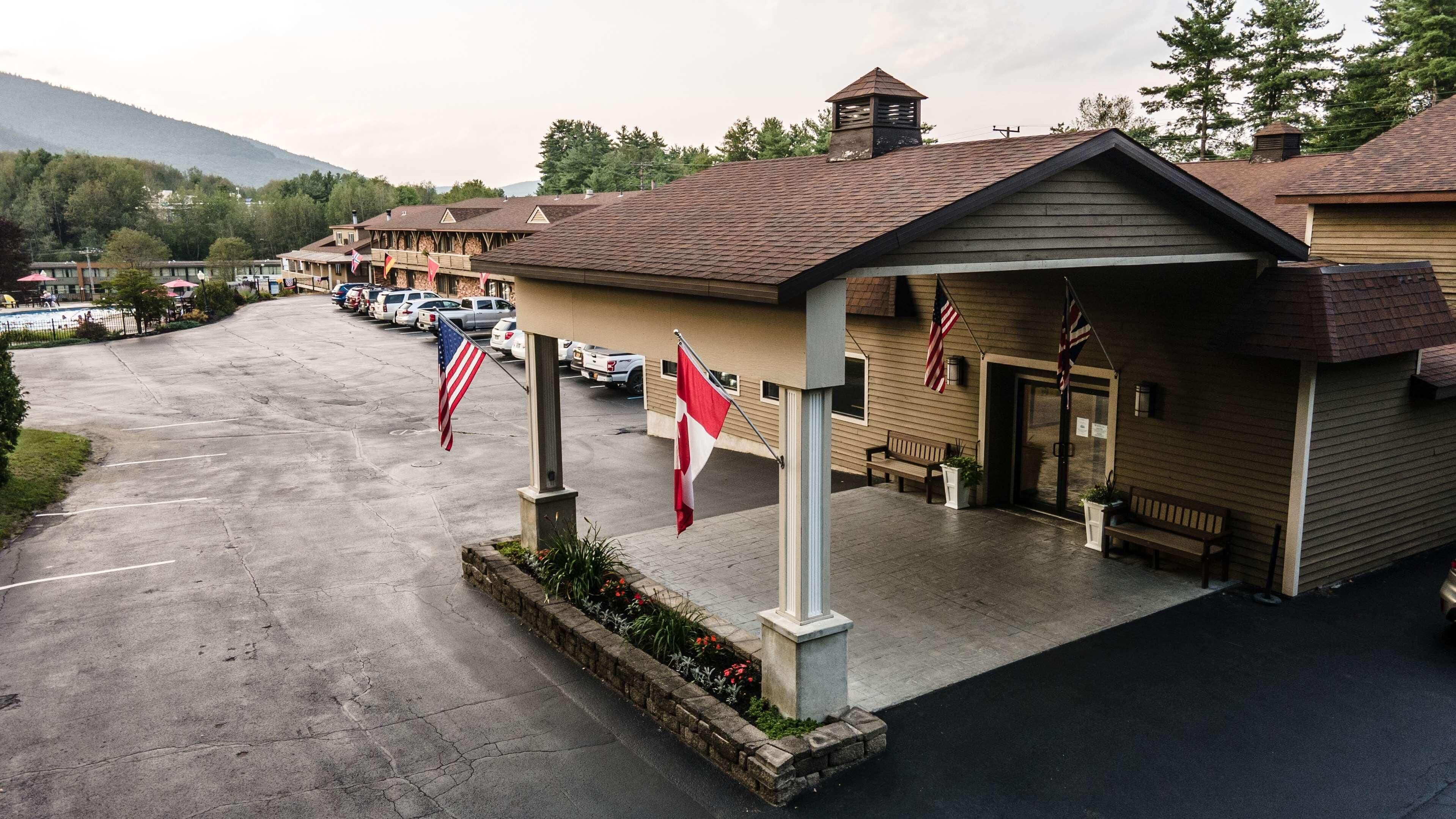A hotel with a covered entrance, American flags, and a parking lot.