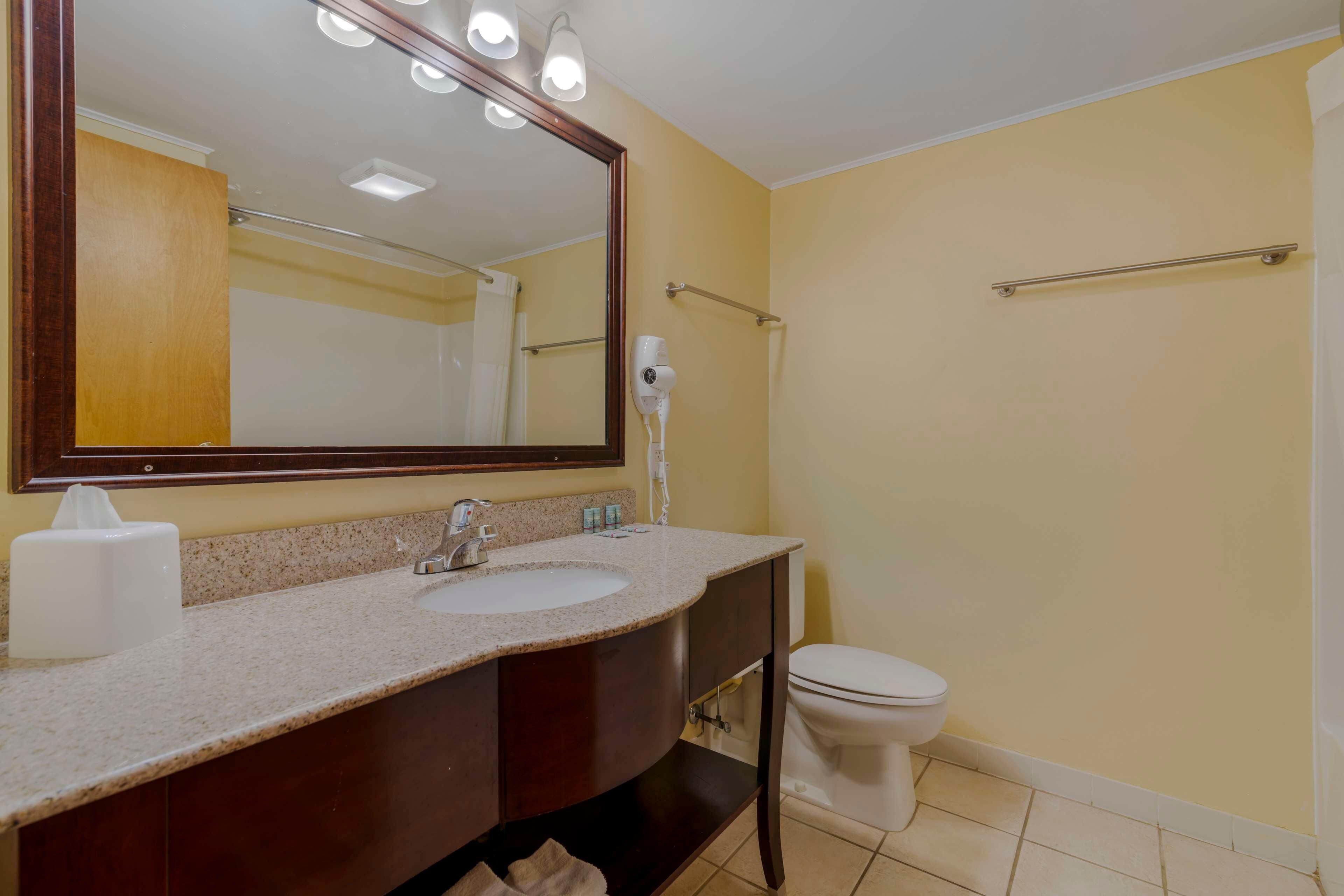 A bathroom with a sink, mirror, towel rack, and toilet.