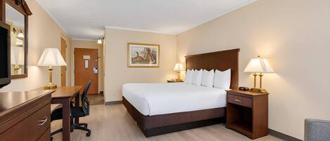 A hotel room with a bed, bedside tables, a desk, a chair, a television, and a painting on the wall.