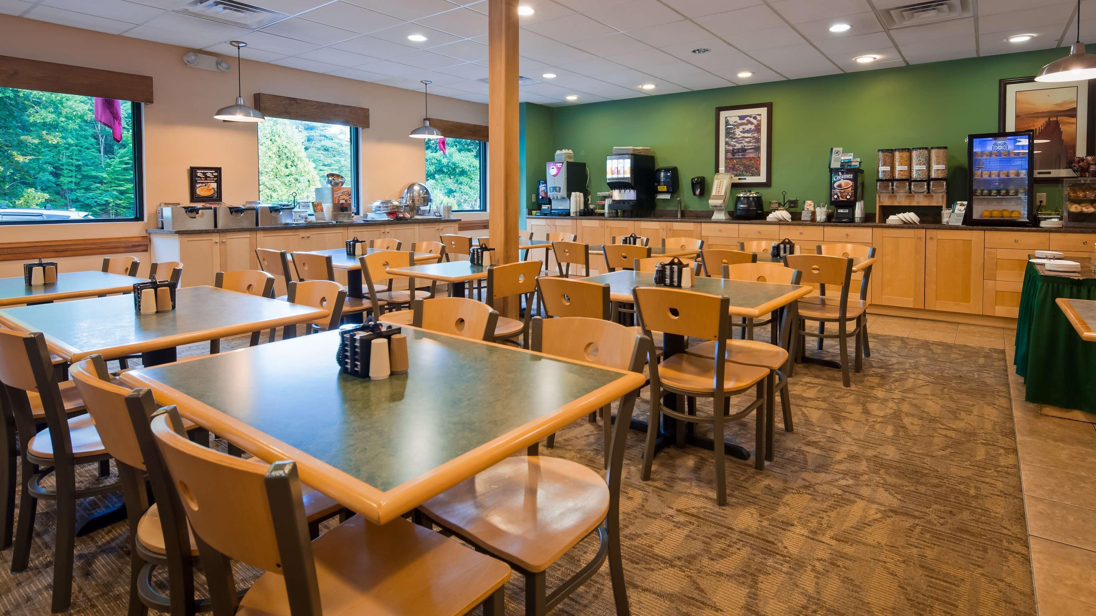A restaurant with multiple tables and chairs, a coffee machine, and a counter with various food items.