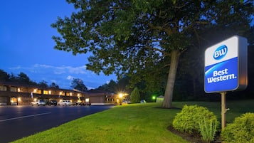 A hotel with a sign reading 'Best Western' and a parking lot with several cars.