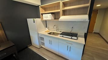 A compact kitchen with a refrigerator, microwave, stove, and sink.